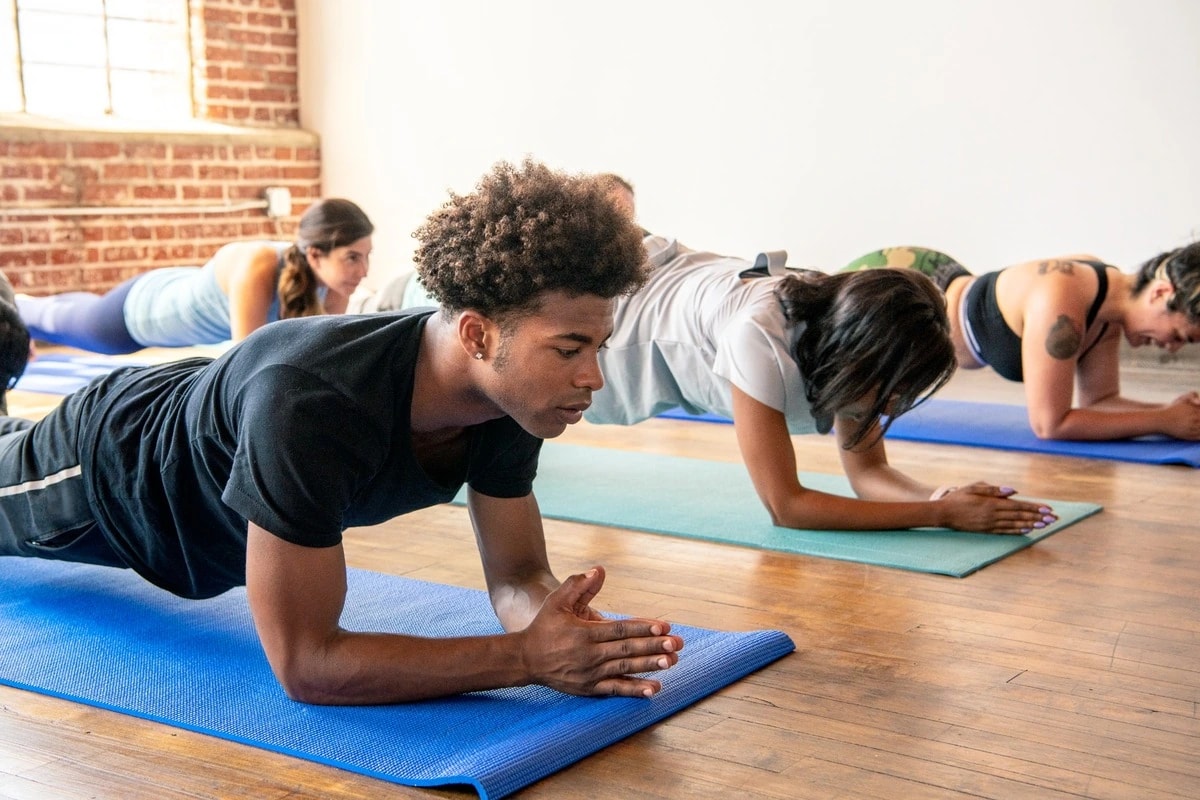 A group holding forearm planks on exercise mats